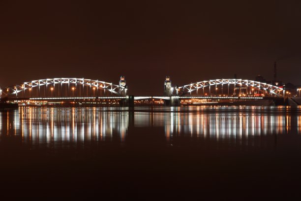 布尔什赫金斯基大桥横跨圣彼得堡涅瓦河，夜晚的灯光倒映在水面上图片下载
