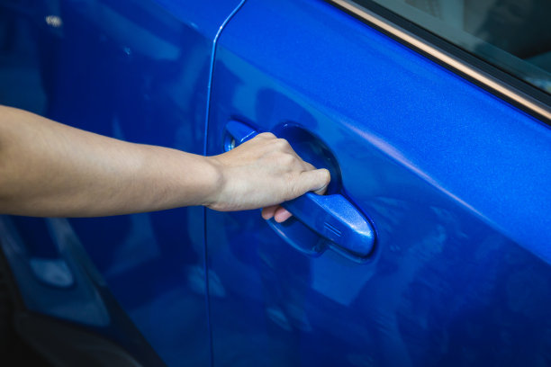 把手和女人的手打开一扇彩色车门的特写。图片下载
