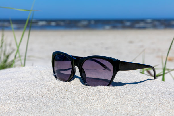 时尚的黑色太阳镜在沙滩上的海洋背景。有选择性的重点图片下载