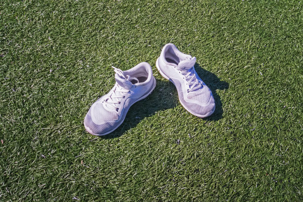 绿色草地上的白色运动鞋。供编辑使用的空间图片下载
