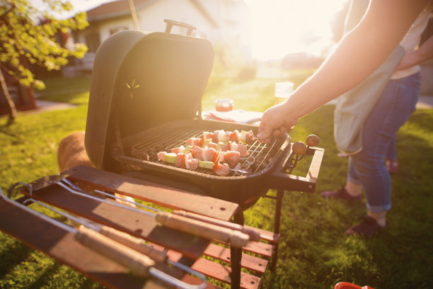男性手在烧烤架上翻肉和蔬菜的特写。图片下载