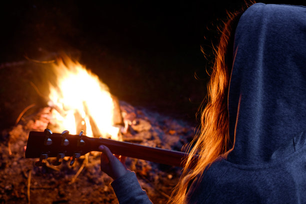年轻的红发女人在篝火旁弹吉他图片下载