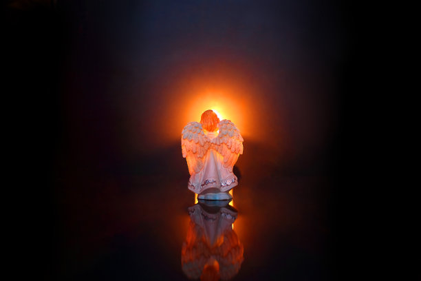 发光背景上的天使。哀悼或情人节的概念。选择性聚焦，特写，侧视图，拷贝空间。图片下载
