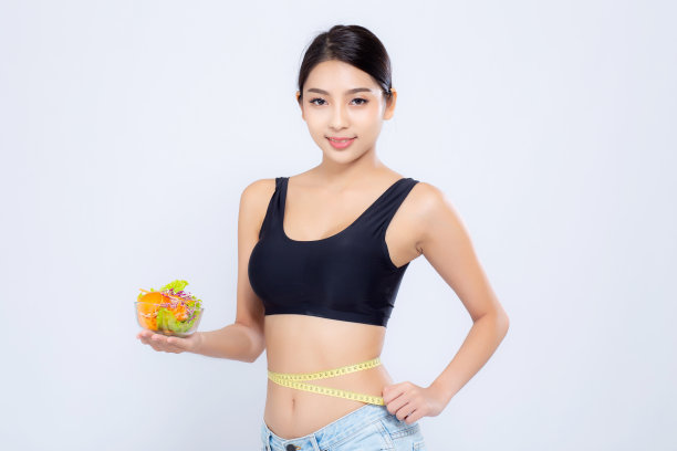 美丽的肖像年轻的亚洲女人微笑着拿沙拉蔬菜食物和测量腰围的体重孤立在白色的背景，女孩节食与脂肪团减掉带测量，保健或健康的概念。图片下载