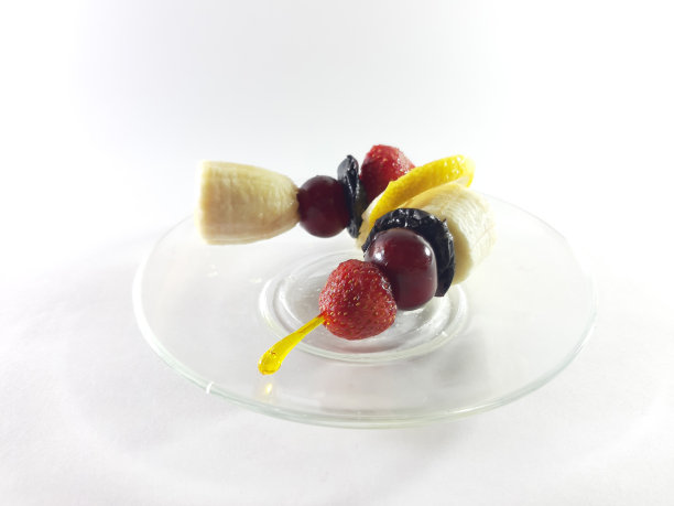 美味的菜。健康食品。把素食放在透明的盘子里。浆果和水果。柠檬和樱桃当点心。现代设计照片。用香蕉、草莓和樱桃做成的点心。图片下载
