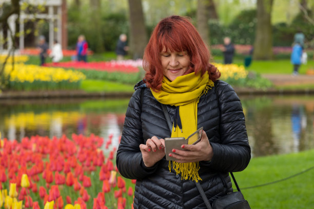 一名女子在用智能手机浏览库肯霍夫公园拍摄的照片图片下载