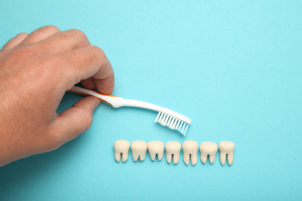 健康洁白的牙齿，蓝色背景的牙膏和手持牙刷图片下载