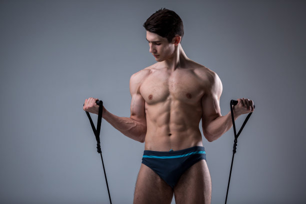 肌肉健康年轻男性古董完美肌肉六块腹肌和裸露的胸部。健美模型训练与拉伸弹性在工作室的黑暗背景。运动训练健身图片下载