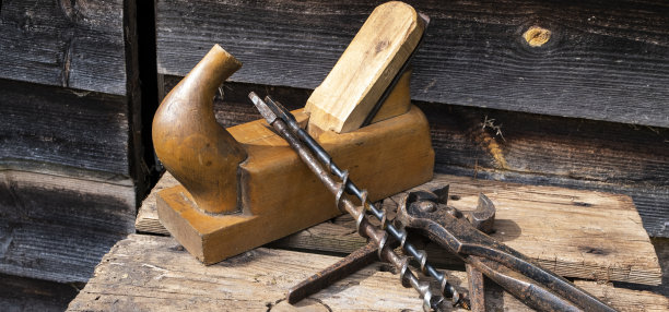 古董手工具，刨钳和钻头。褐色的旧木板。复制空间，全景照片。图片下载