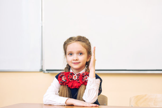 美丽的女童女开心地笑着坐在教室的课桌前图片下载