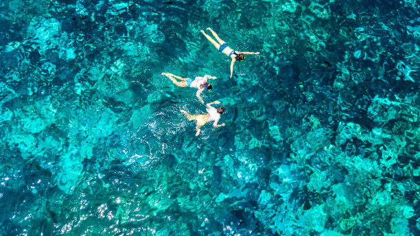 鸟瞰家庭浮潜从上面，母亲和孩子浮潜游泳在清澈的热带海水与珊瑚在泰国暑假期间图片下载