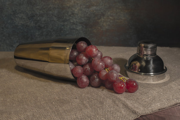一把红葡萄从一个镜子摇瓶倒在亚麻桌布上。葡萄浆果质地，低调图片下载