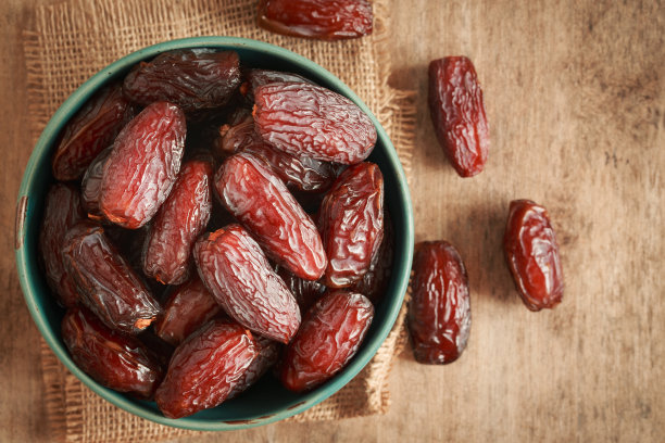 近距离的照片椰枣水果杯上的麻布，木制桌子的背景。椰枣、棕榈果干是健康的零食。图片下载