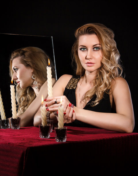 漂亮的年轻女人，在镜子旁点蜡烛图片下载