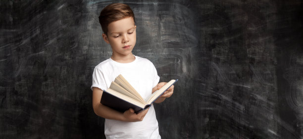 英俊的男生站在黑板旁边看书图片下载