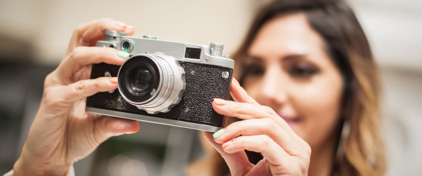 一个女人在城市街道上用老式胶卷相机拍照图片下载
