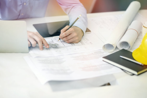 年轻的工程师或建筑师，在他的办公室里处理蓝图和笔记本电脑。图片下载