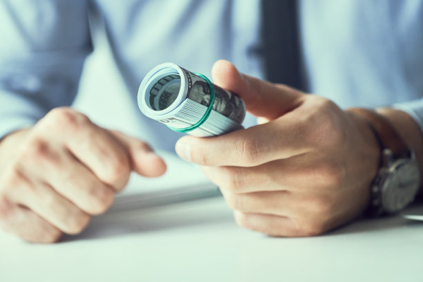 一名男子拿出一排美钞，手里拿着现金。货币信贷的概念。健美的图片。图片下载