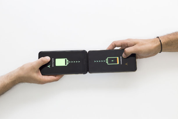 两只手拿着黑色智能手机，正在无线充电。智能手机无线充电。他们互相供应。白色背景。图片下载