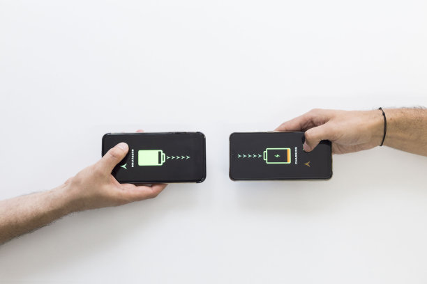 两只手拿着黑色智能手机，正在无线充电。智能手机无线充电。他们互相供应。白色背景。图片下载
