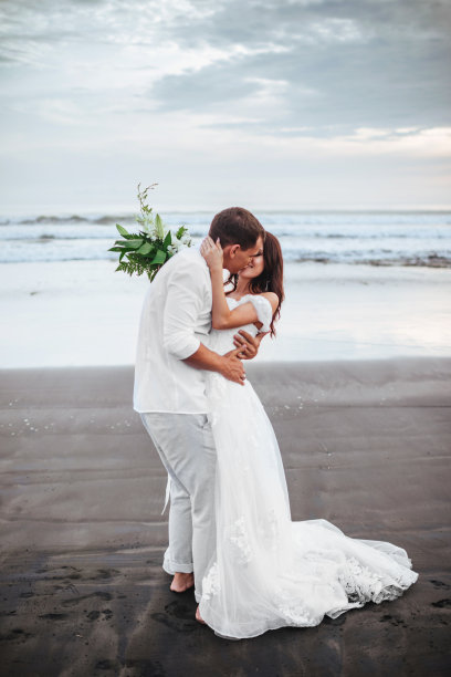 优雅华丽的新娘和新郎走在海边的日落时间。图片下载