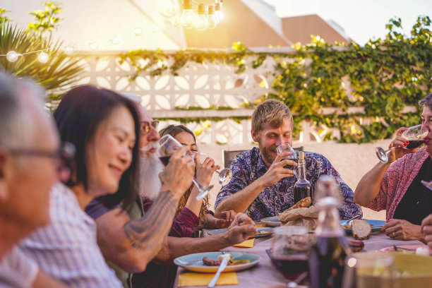 快乐的家庭吃和喝葡萄酒在户外露天烧烤晚餐-成熟和年轻人有乐趣的烧烤周日餐-食物和夏天的生活方式概念-关注金发男人的脸图片下载