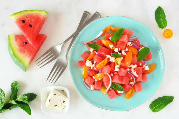 西瓜和番茄沙拉，一个蓝色盘子的俯视图，大理石背景图片下载