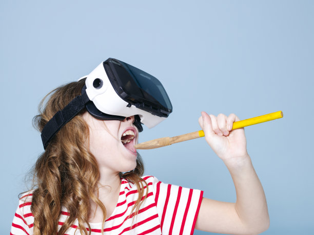 微笑积极的女孩戴着虚拟现实眼镜眼镜耳机是用勺子做饭，在蓝色的背景图片下载