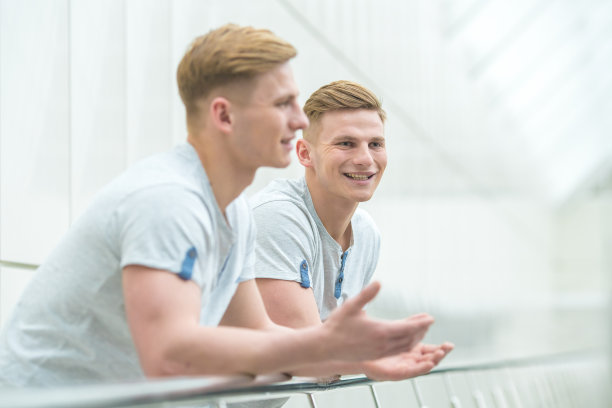 兄弟俩笑着站在办公室阳台上打手势图片下载