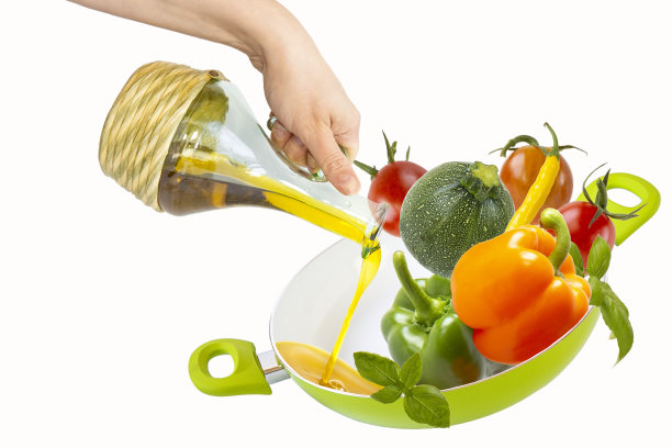 女人用手把植物油从瓶子里倒进盛着蔬菜的煎锅里。白色背景上的孤立物体图片下载