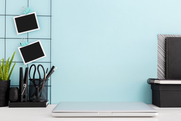 笔记本电脑和办公用品，室内植物和蓝色的墙壁。模拟。图片下载