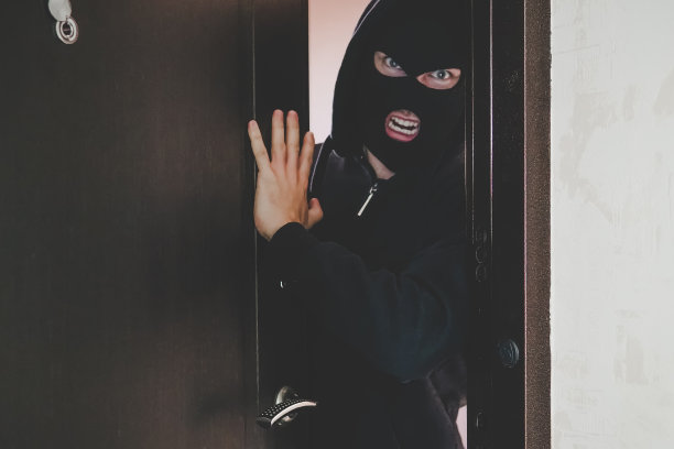 戴着黑色面罩的邪恶歹徒破门而入，闯入房间并威胁居民。犯罪和暴力的概念。盗匪，强盗活动，敲诈勒索，土匪活动，图片下载