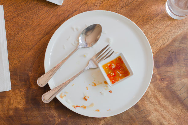 木桌上放着盛有鱼露的盘子里的食物残渣图片下载