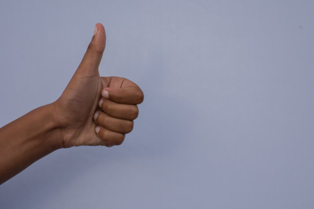 蓝色背景下竖起大拇指的手势图片下载