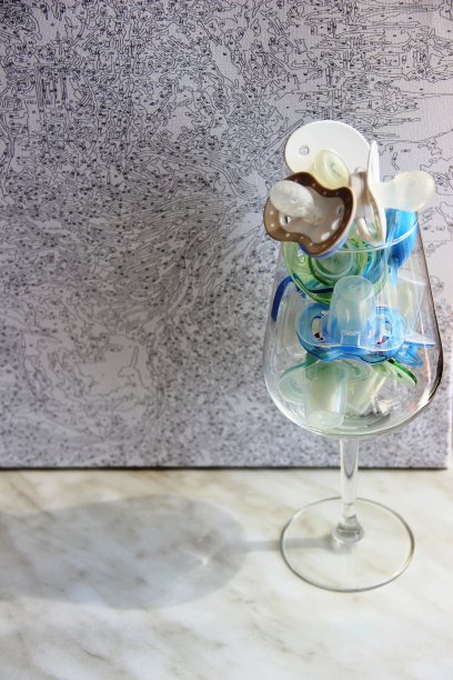 一个装满旧奶嘴的杯子——灰色背景下的婴儿奶嘴。抽象化的喝一杯婴儿图片下载