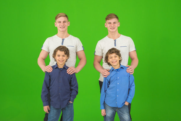 四个快乐的兄弟站在绿色的背景上图片下载
