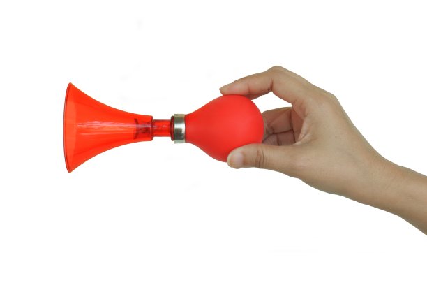 亚洲女人的手在白色的背景上吹着红色的号角。图片下载