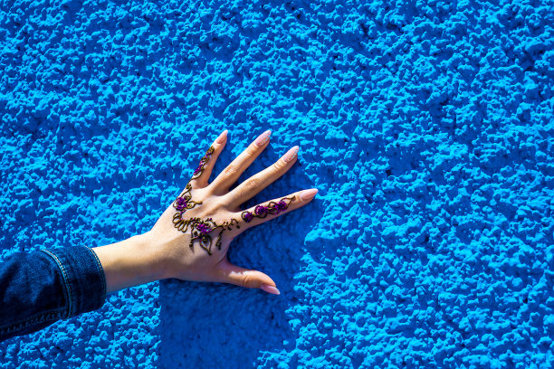 蓝色墙壁的背景上有一个传统的指甲花纹身。摩洛哥拉巴特图片下载