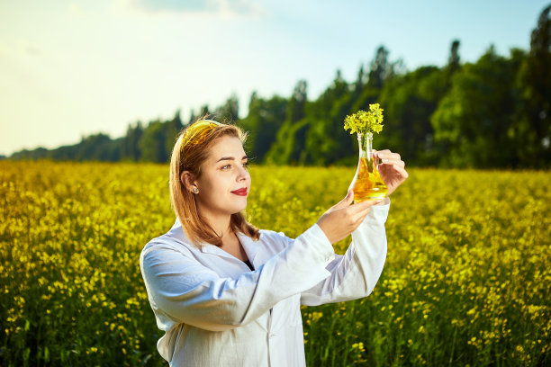 一位年轻漂亮的生物学家或农学家在一片菜地上检查菜籽油的质量。农业的概念图片下载