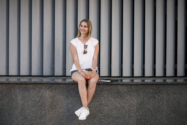 一名微笑的欧洲妇女走在城市街道上，手里拿着咖啡外卖图片下载