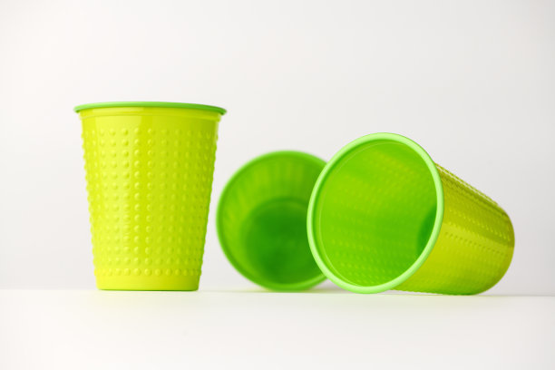 白色背景上散落着绿色塑料杯。孤立的背景。图片下载