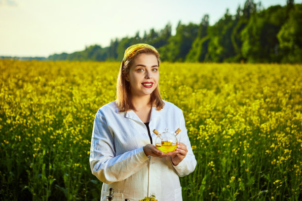 一位年轻漂亮的生物学家或农学家在一片菜地上检查菜籽油的质量。农业的概念图片下载