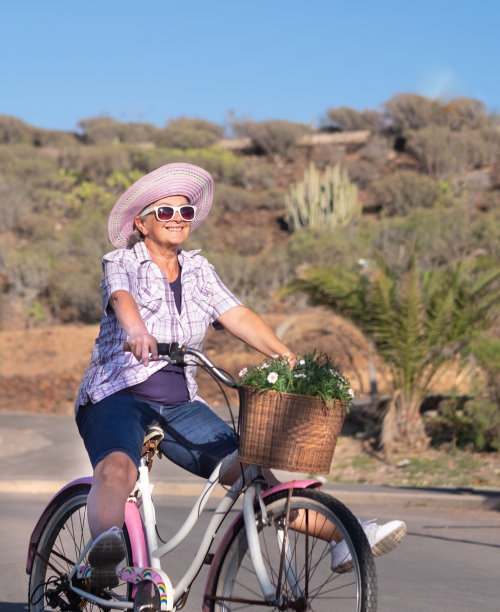 资深快乐女人享受自行车与乐趣。退休人士的健康生活方式。背景是蓝天和山脉。高加索人图片下载