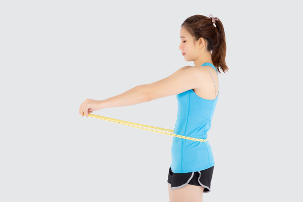 美丽苗条的年轻亚洲女子测量尺瘦腰穿制服健身孤立的白色背景，亚洲女孩减肥与饮食运动和锻炼健康和保健身体。图片下载