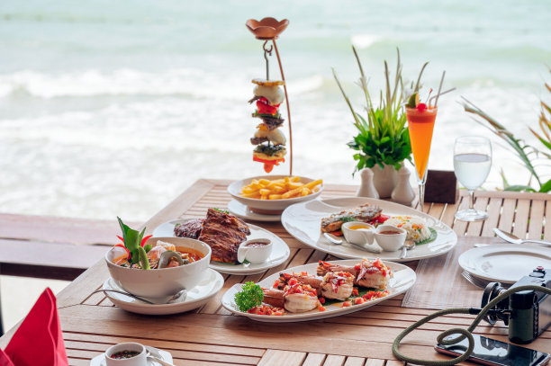 热带海洋的木制餐桌上的食物有辣虾、炸排骨、冬阴功、牛排图片下载