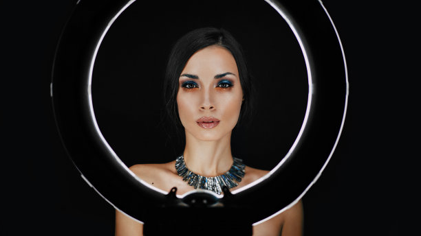 一个漂亮的年轻白种女孩与美丽的化妆从一个圆形灯后面看着人像照片拍摄图片下载