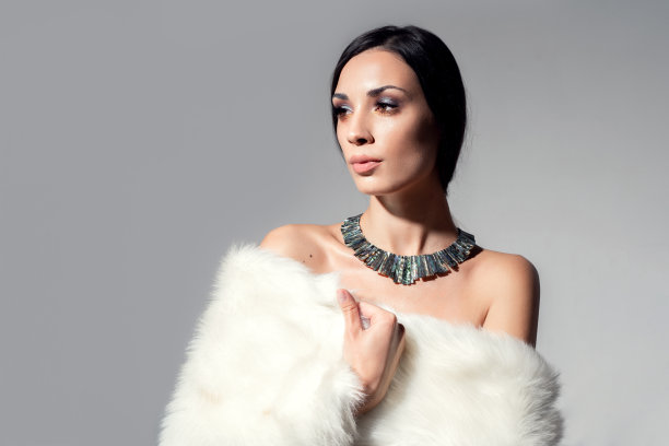 一个美丽的年轻白人女孩的肖像赤裸的肩膀和美丽的晚上化妆穿着人工白色毛皮图片下载
