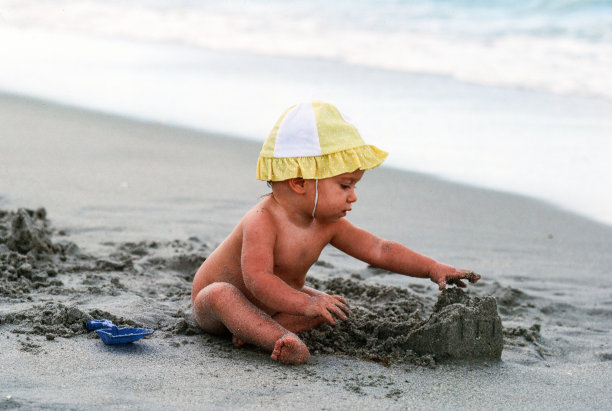 婴儿在海边的沙滩上玩耍图片下载