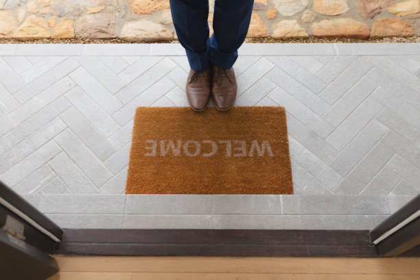 男子站在家门口的欢迎垫附近素材图片