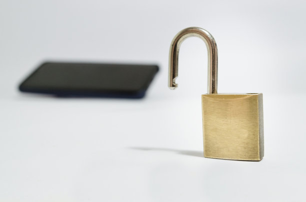 概念照片安全在手机上。一个打开的挂锁在前景和一个手机在背景上的白色背景。图片下载